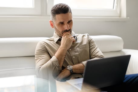 man looking intently at his laptop in his home